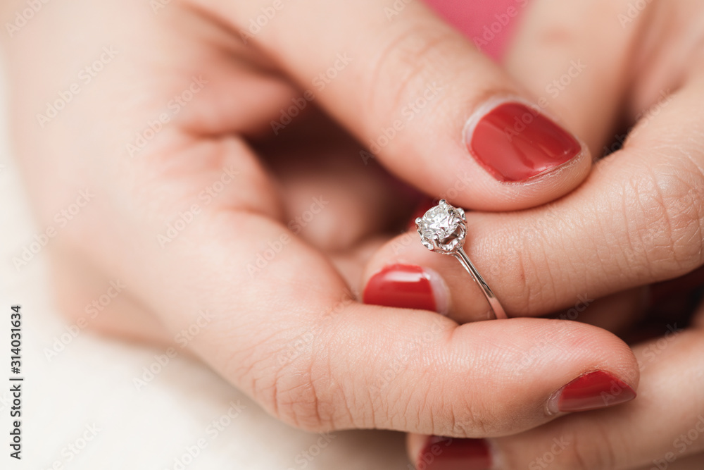 Close up of an elegant engagement diamond ring on woman finger with pink sweater winter clothe. Close up of an elegant engagement diamond ring on woman finger with pink sweater winter clothe.