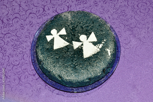 Festive cake decorated with silhouettes of angels on a lilac background.