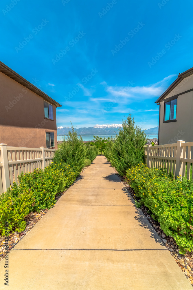 Pathway with plants and picket fence amid houses with view of lake and mountain Pathway with plants and picket fence amid houses with view of lake and mountain