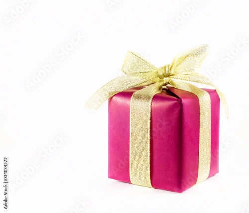 Red gift box with gold ribbon on a light background with space for text. © Rika777