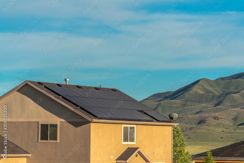 Solar panels on gable roof of home against mountain and blue sky background