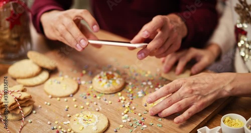 Handheld view of man photographing Christmas cookies in the kitchen