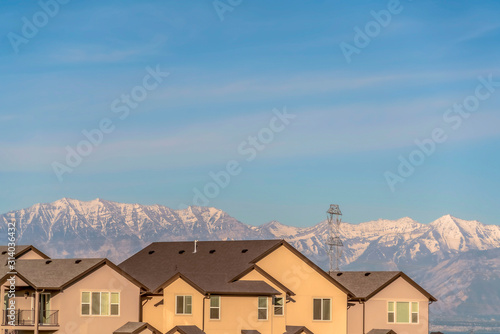 Exterior of homes with beige walls and balcony against snow capped mountain © Jason