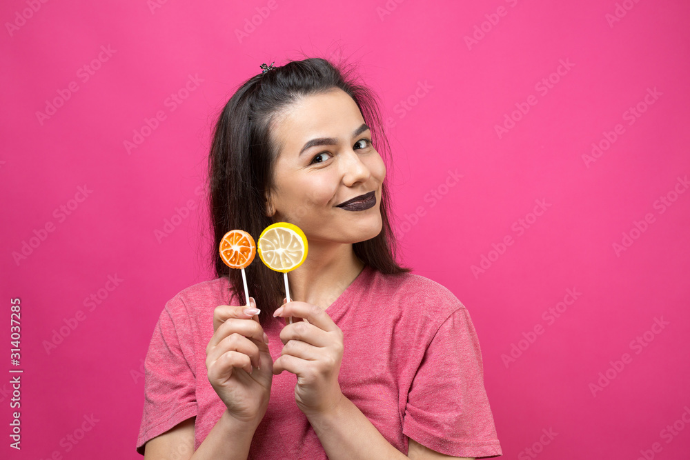 Portrait of lovely sweet beautiful cheerful woman with straight brown hair holding a lollipop near the eyes. Portrait of lovely sweet beautiful cheerful woman with straight brown hair holding a lollipop near the eyes.