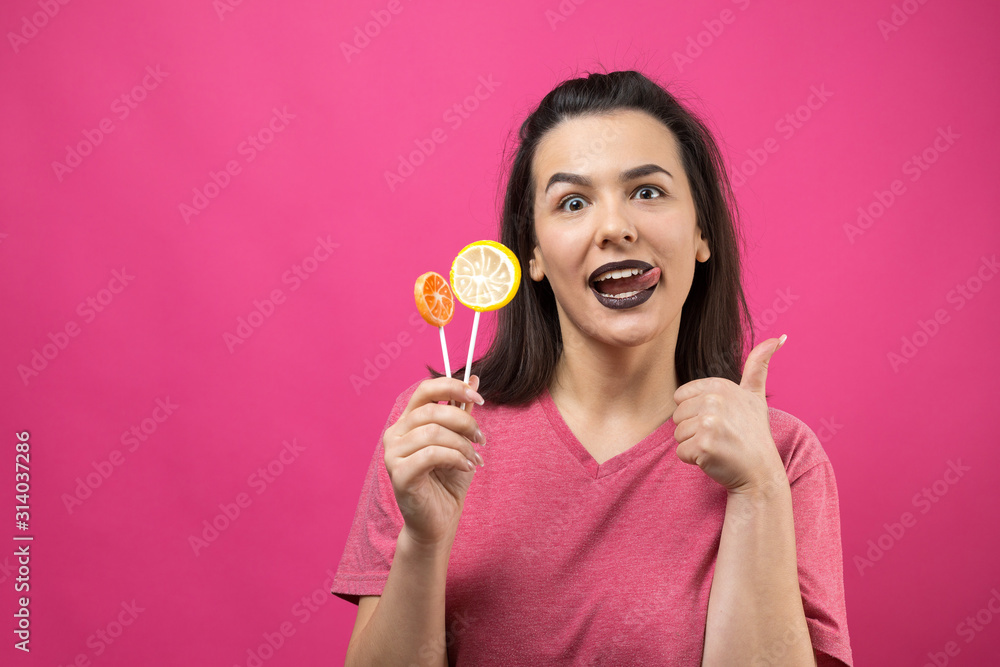 Portrait of lovely sweet beautiful cheerful woman with straight brown hair holding a lollipop near the eyes. Portrait of lovely sweet beautiful cheerful woman with straight brown hair holding a lollipop near the eyes.