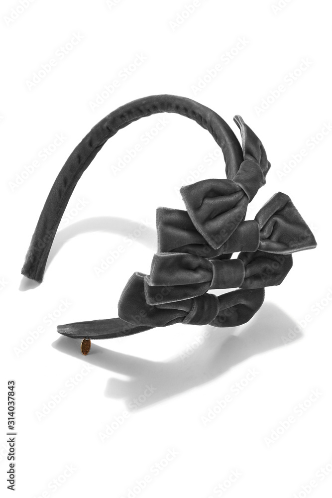 Subject shot of a gray hairband with a row of gray velvet bows and a little golden charm. The stylish headband is isolated on the white background. Subject shot of a gray hairband with a row of gray velvet bows and a little golden charm. The stylish headband is isolated on the white background.