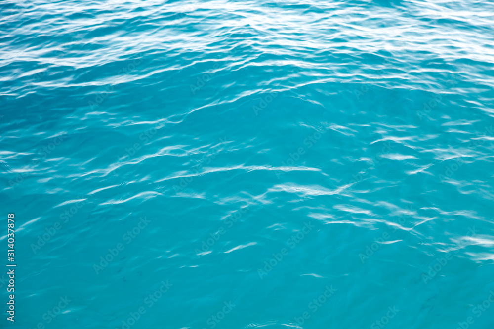 Clear water texture in blue. Background of the ocean and the sea backlit by the sun. Clear water texture in blue. Background of the ocean and the sea backlit by the sun.