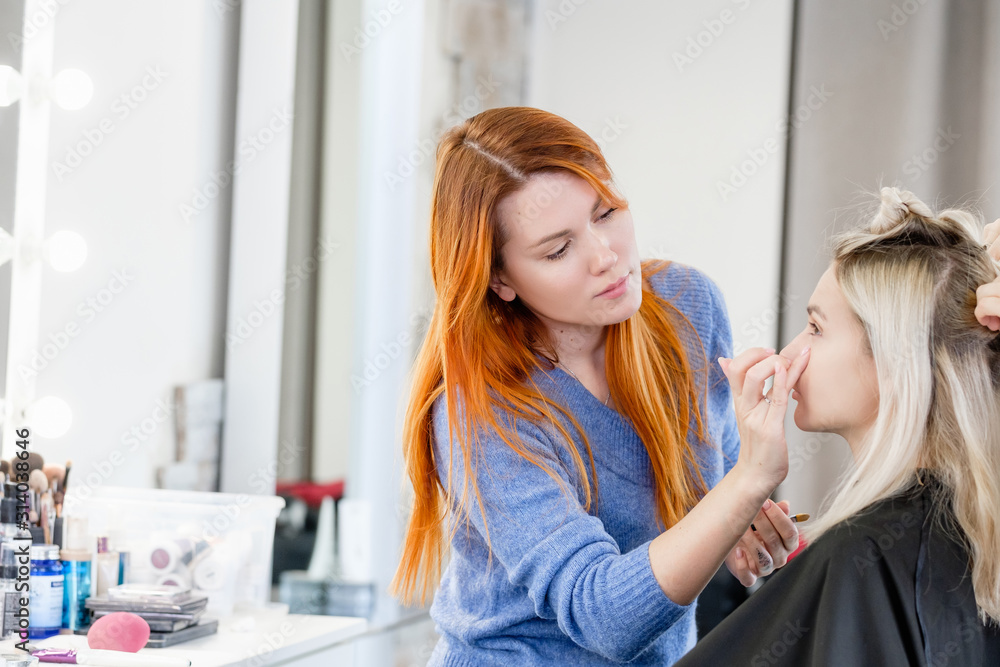 Young female madel visits professional stylist, makes creative hairstyle and makeup for important social event. Young woman in makeup artist chair. Client of fashionable salon, luxury beauty studio Young female madel visits professional stylist, makes creative hairstyle and makeup for important social event. Young woman in makeup artist chair. Client of fashionable salon, luxury beauty studio