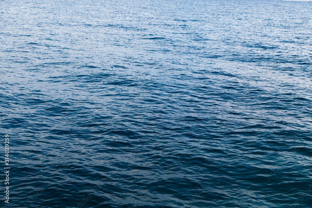 Clear water texture in blue. Background of the ocean and the sea backlit by the sun. Clear water texture in blue. Background of the ocean and the sea backlit by the sun.