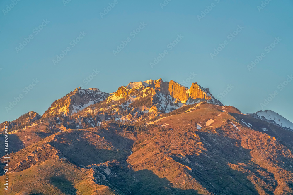 Striking mountain peak with rugged slopes against blue sky on a sunny day