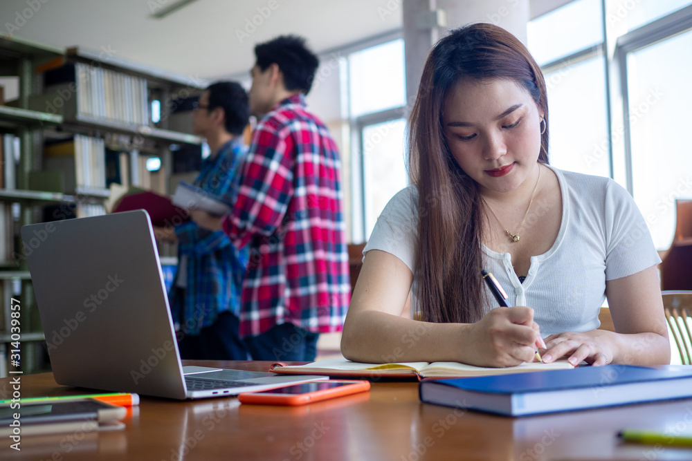 Asian female students sit and do their homework in the library. Asian female students sit and do their homework in the library.