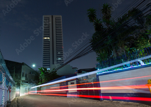 Car lights passing by a small street in Bangkok at night