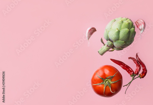 Organic vegetables artichoke ripe juicy tomato hot chili peppers garlic cloves floating levitating on pink background. Creative food poster. Mediterranean cuisine healthy diet ingredients