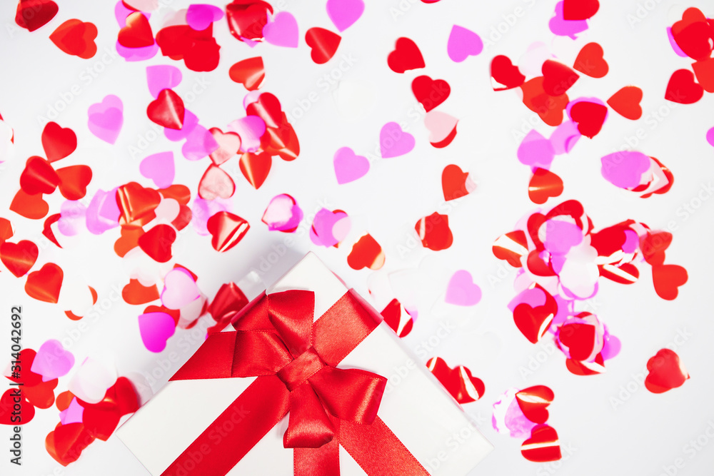 Present box with decorative hearts confetti on white background. Abstract backdrop. Love and romance concept. Present box with decorative hearts confetti on white background. Abstract backdrop. Love and romance concept.