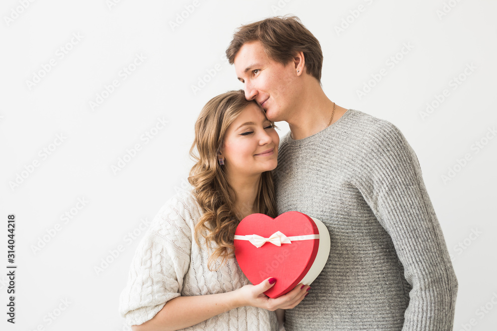 Valentine's day, holiday and gift concept. Happy young couple with valentine's day present isolated on a white background. Happy Man giving a gift to his girlfriend. Valentine's day, holiday and gift concept. Happy young couple with valentine's day present isolated on a white background. Happy Man giving a gift to his girlfriend.