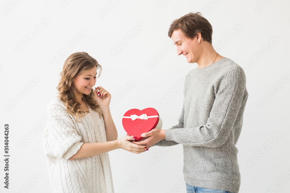 Valentine's day, holiday and gift concept. Happy young couple with valentine's day present isolated on a white background. Happy Man giving a gift to his girlfriend. Valentine's day, holiday and gift concept. Happy young couple with valentine's day present isolated on a white background. Happy Man giving a gift to his girlfriend.