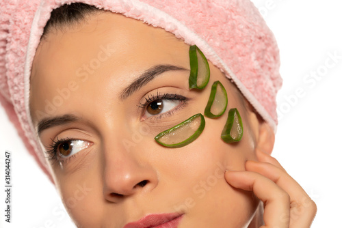 Young beautiful woman posing with a slicesf of aloe vera onher face photo