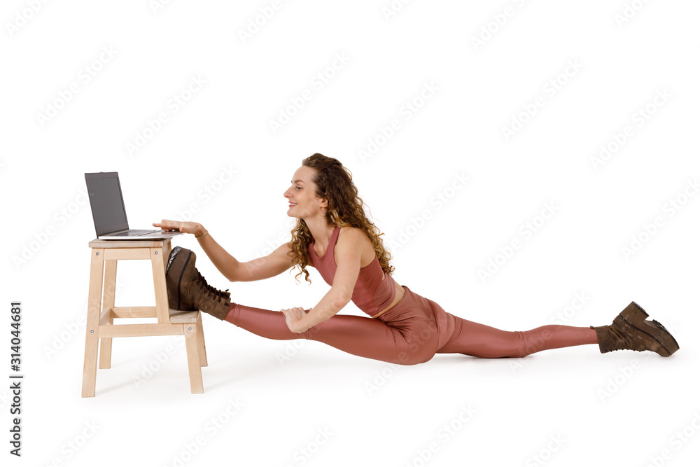Young woman sitting in the splits and works on a laptop Young woman sitting in the splits and works on a laptop