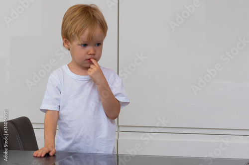 Obraz na plátně A boy holding his fingers in his mouth