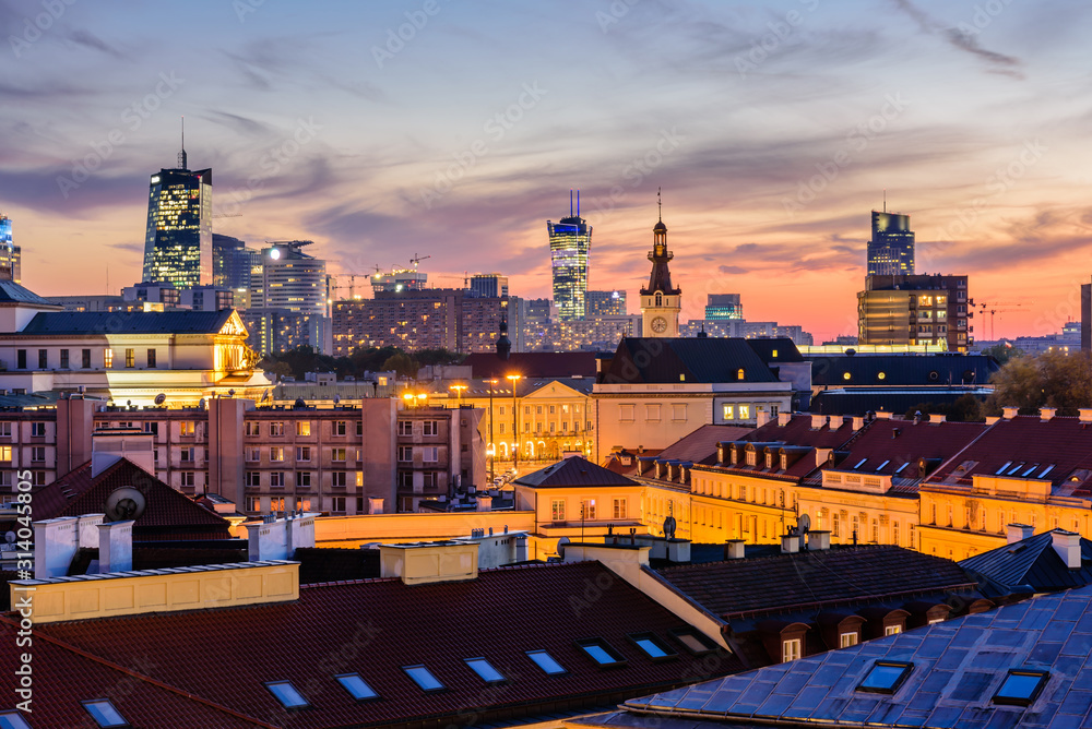 Fototapeta premium Cityscape of Warsaw at night. Roofs of the old town and skyscrapers against a beautiful sunset sky with illumination, Warsaw, Poland