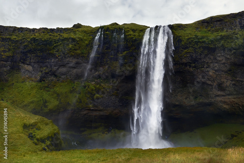A powerful waterfall among the rocks covered with green moss. Iceland. . Dark fabulous atmosphere, vintage. 