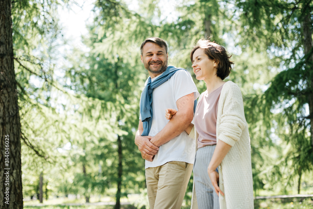 Middle-aged couple walking in the park holding hands. Middle-aged couple walking in the park holding hands.