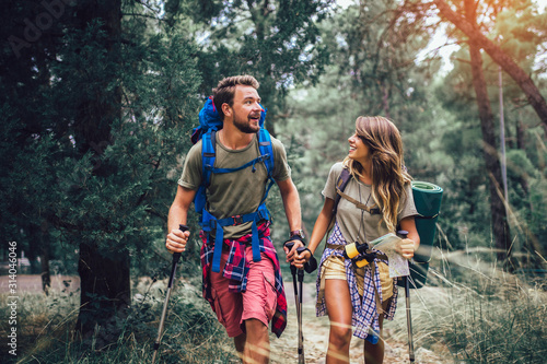Smiling couple walking with backpacks over natural background photo