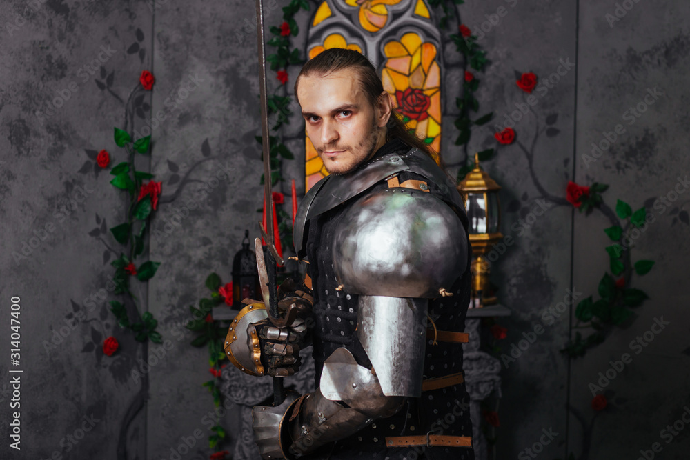 Portrait of a medieval knight with a two-handed sword. Warrior in the studio on a dark background.
