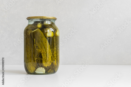 Fermented vegetables. Glass jar with homemade pickled ugly cucumbers on a white background. Copy space, close-up