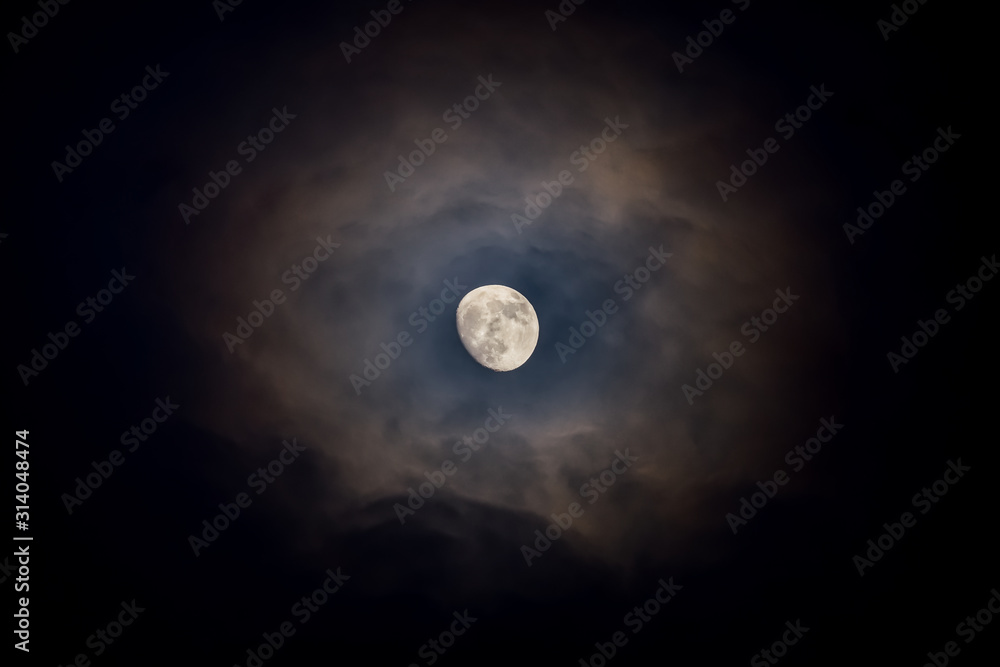 Waxing moon encircled by clouds