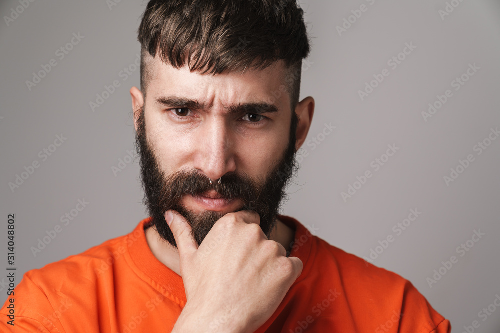 Image of young bearded man with nose jewelry wearing orange shirt Image of young bearded man with nose jewelry wearing orange shirt