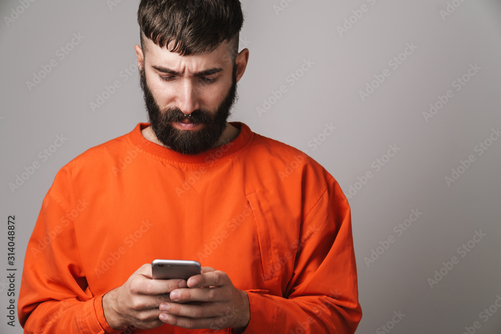 Image of young bearded man with nose jewelry holding smartphone Image of young bearded man with nose jewelry holding smartphone