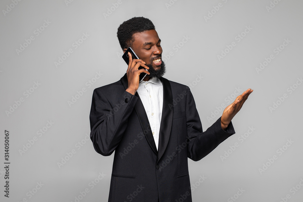 Cheerful businessman talking on mobile phone isolated on gray background Cheerful businessman talking on mobile phone isolated on gray background