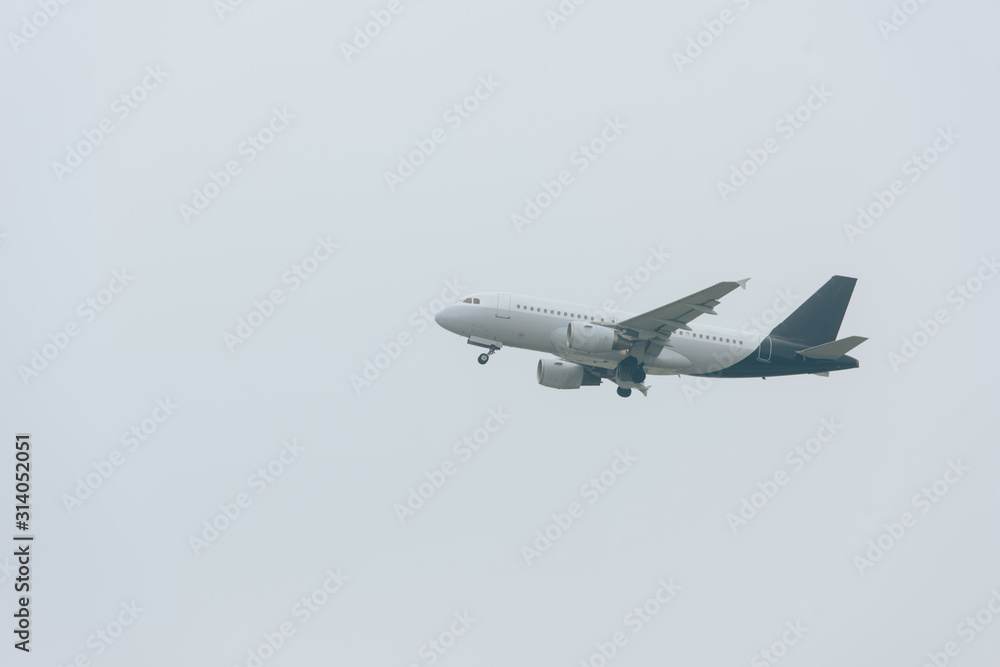 Fototapeta premium Low angle view of airplane landing in cloudy sky