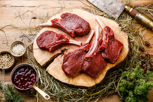 Billede på lærred Raw sliced Venison Ribs and meat cleaver on wooden background
