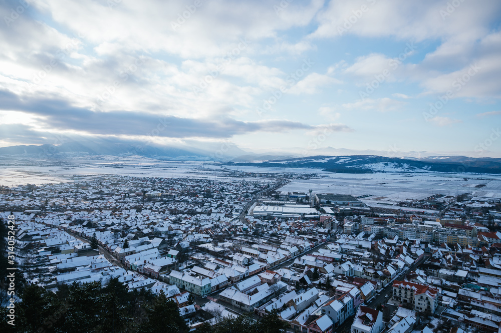 Landscape of a European village with snowy fields in the background and with clear sky