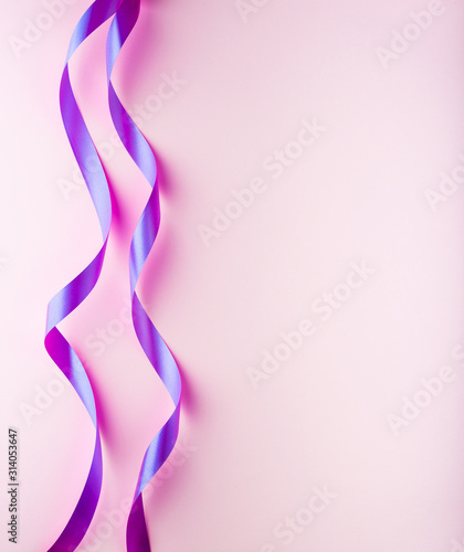 Curled neon pink ribbon on a light pink background. Festive banner with space for text. Greeting card for sale, Happy Valentine's Day, birthday party.