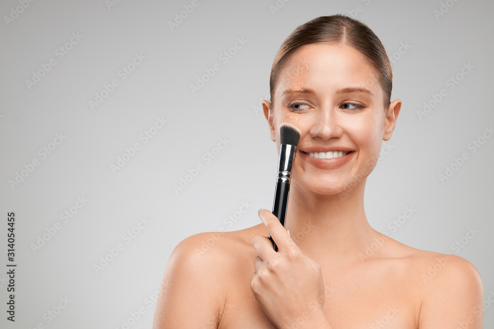 Beautiful caucasian girl with pure skin putting on powder. Beautiful caucasian girl with pure skin putting on powder.