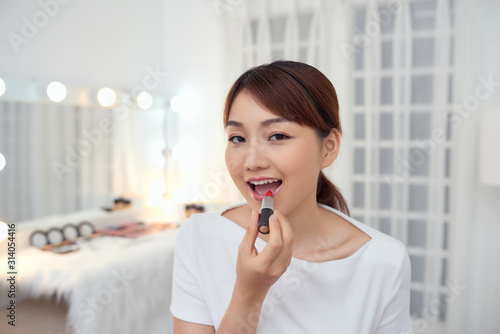 Portrait of Beautiful young Asian girl applying lipstick