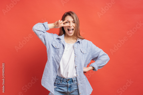 Funny, carefree girl having fun isolated on a red background with open mouth