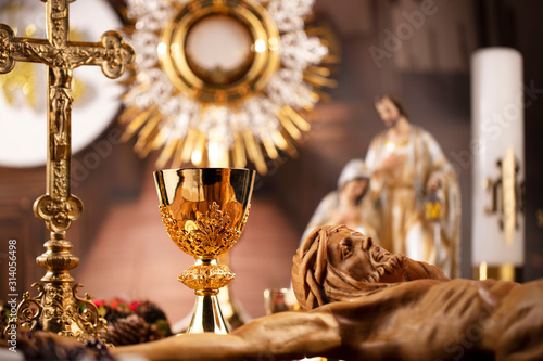 Catholic concept background.  The Cross, monstrance, Jesus figure, Holy Bible and golden chalice on the rustic wooden table.