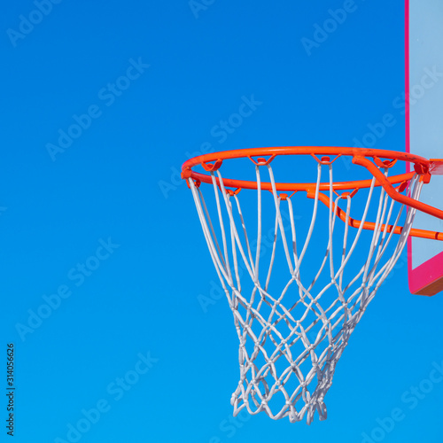 Square Close up on a basketball net against blue sky near sunset © Jason