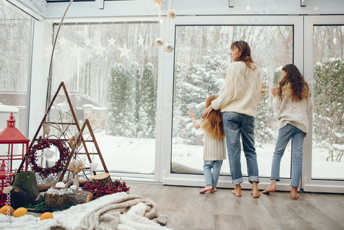 Beautiful mother with children. Family at home. People standing near winter windows