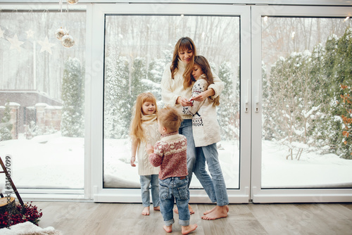 Beautiful mother with children. Family at home. People standing near winter windows
