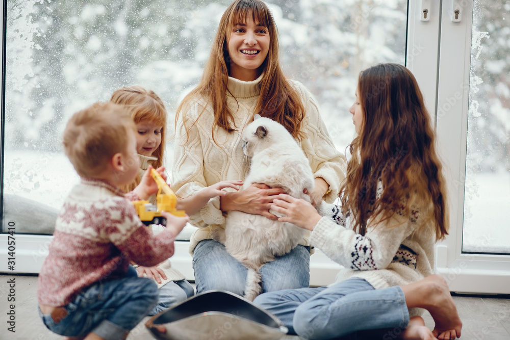 Beautiful mother with children. Family at home. People sitting near winter windows