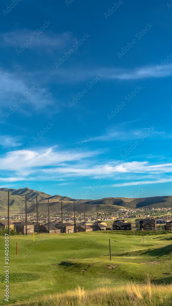 Vertical frame Golf course fairway and putting green with flagsticks under blue sky and clouds Vertical frame Golf course fairway and putting green with flagsticks under blue sky and clouds