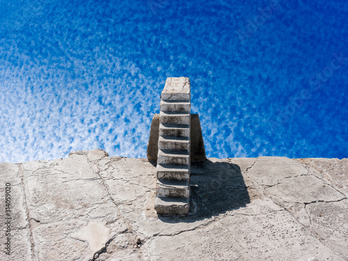 Old stone stairway back view under vanishing white cirrocumulus clouds in blue sky photo