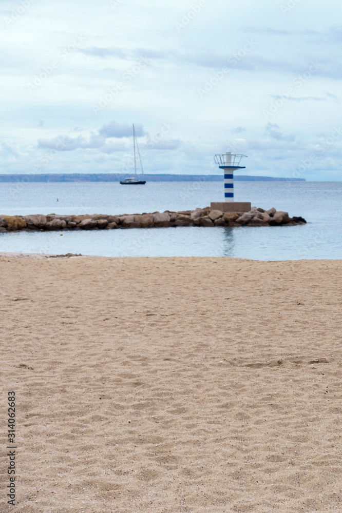 wide sandy beach on the background of the sea and the lonely lighthouse, in the Spanish resort of Magaluf