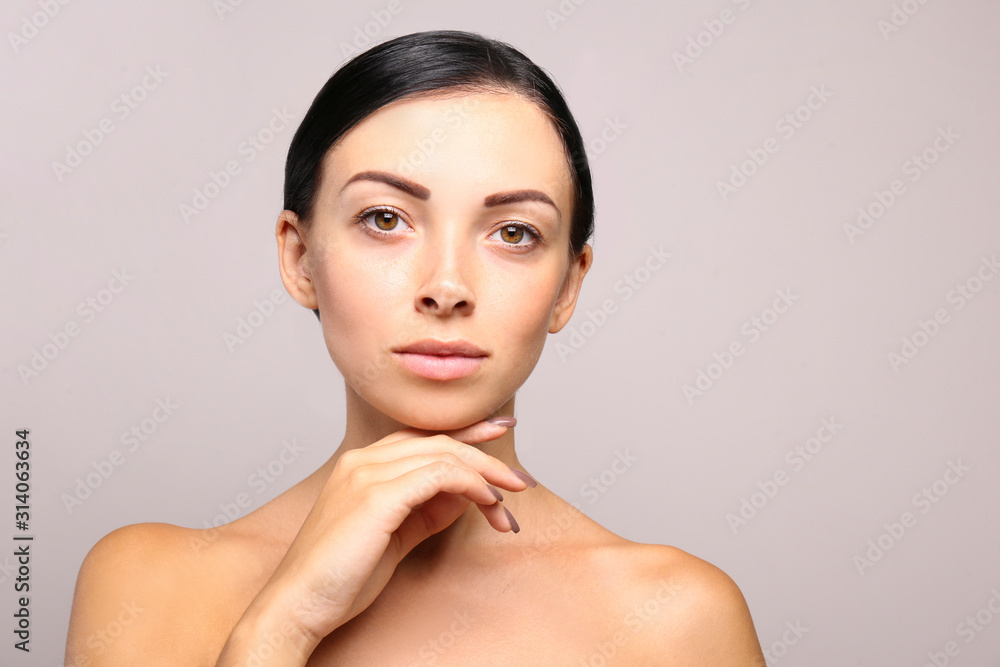 Portrait of young beautiful woman with perfectly clean face skin. Female with long black hair tied in ponytail smiling showing skincare results. Close up, copy space background. Portrait of young beautiful woman with perfectly clean face skin. Female with long black hair tied in ponytail smiling showing skincare results. Close up, copy space background.