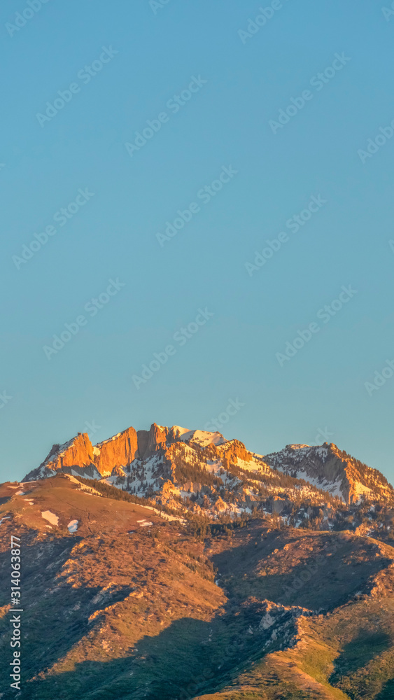 Vertical Scenic view of a mountain peak with rugged slopes and dusted with snow